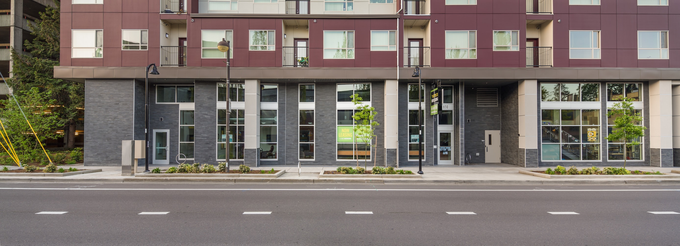 Panoramic shot of a commercial mixed use building that used Norstone Aksent Grey 3D Panels on the first floor facade.